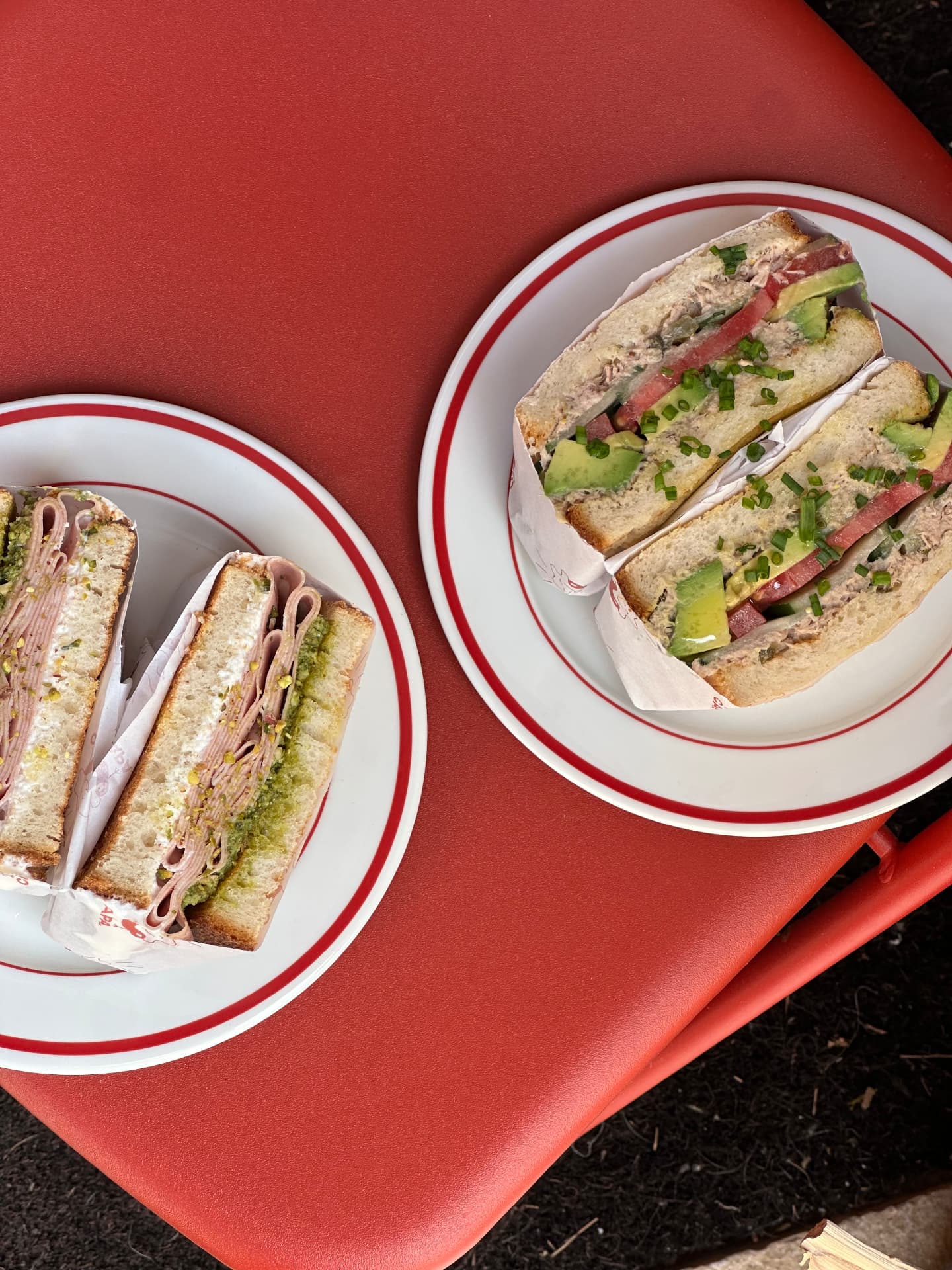 Dos bocadillos en platos sobre mesa roja de terraza